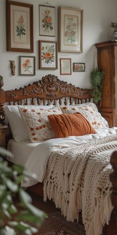 a bed sitting in a bedroom next to pictures on the wall and wooden headboard