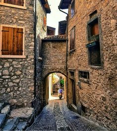 an alley way with cobblestone stone buildings and wooden shutters on either side