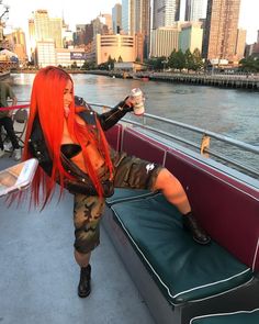 a woman with red hair sitting on top of a boat in the water holding a drink