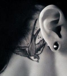 an ear with a bird tattoo on it