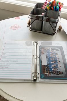 a binder with pens and pencils on top of a table