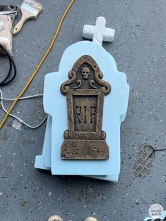 an old tombstone with a cross on the ground next to some shoes and other items