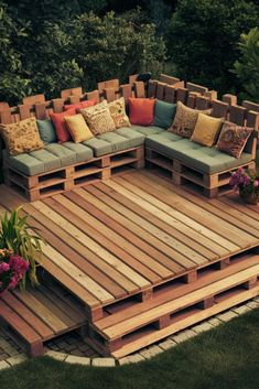 a couch made out of wooden pallets in the middle of some grass and flowers