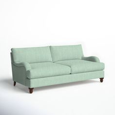 a light green couch sitting on top of a white floor next to a wooden frame