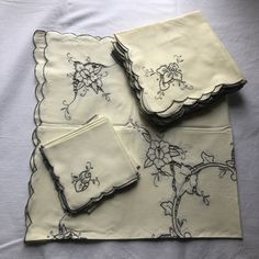 four napkins with embroidered flowers on them