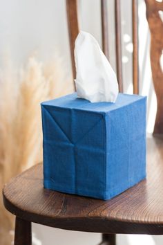 a tissue box sitting on top of a wooden table next to a chair with a blue cloth wrapped around it