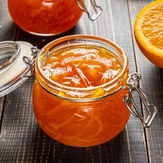 a jar filled with liquid sitting on top of a wooden table next to an orange