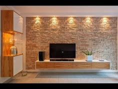 a living room with a large television on the wall next to a plant in a vase