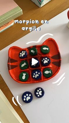 an orange and blue cat tray with paw prints on it, next to other items