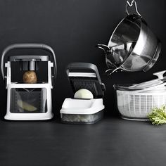 an assortment of kitchen appliances and utensils on a black countertop, with one being used as a grater