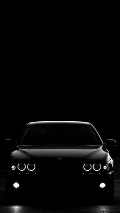 a black and white photo of a car in the dark with its headlights turned on