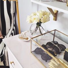 a white dresser topped with lots of gold accessories