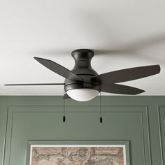 a ceiling fan mounted to the ceiling in a room with green walls and wood paneling