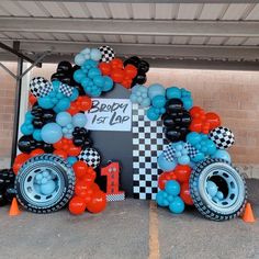 a car made out of tires and balloons with a sign that says happy 1st birthday