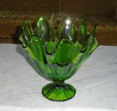 a green glass vase sitting on top of a white marble counter next to a window