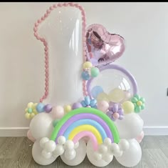 an assortment of balloons in the shape of a rainbow and a vase with a heart