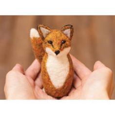 a hand holding a tiny stuffed fox in it's palm