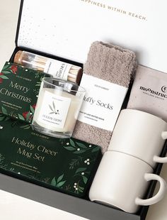 the holiday gift box contains two mugs, a candle and some other personal care items