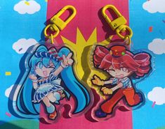 two cartoon key chains are shown on a colorful background with clouds and sun in the sky