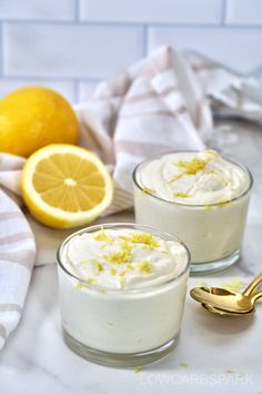 two small glasses filled with lemon custard and topped with whipped cream next to sliced lemons