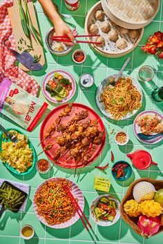 an overhead view of many plates and bowls of food on a green tiled table top