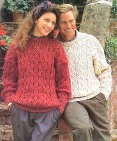 a man and woman sitting next to each other in front of a brick wall smiling