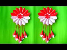 two red and white origami wind chimes hanging on green wall with hearts