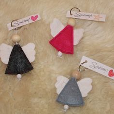 three little angel ornaments with name tags attached to them on a fur surface in front of a white background