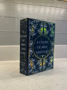 a court of mist and fury book sitting on top of a countertop next to a wall