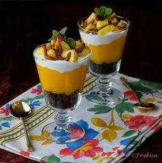 two desserts are sitting on a table with spoons