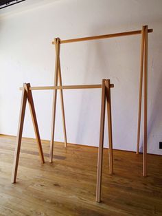 three wooden poles are standing in the middle of a room with white walls and wood flooring