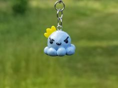 a little blue bird with a yellow crown on it's head hanging from a metal chain