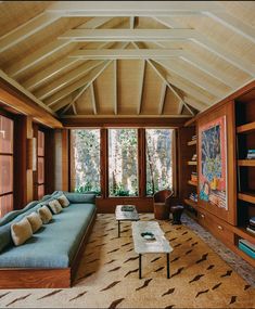 a living room with couches, tables and bookshelves in front of large windows