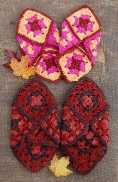 three crocheted mitts are laying on the ground with autumn leaves around them