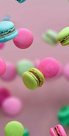 colorful macaroons flying in the air with pink and green colors behind them on a pink background