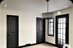 an empty room with two black doors and a chandelier