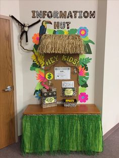 an information hut with grass and flowers on the front table, next to a door