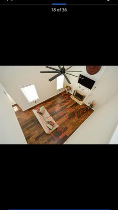 an aerial view of a living room with wood flooring and ceiling fan on the wall