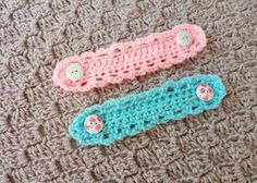 two crochet ear warmers sitting on top of a knitted blanket next to each other