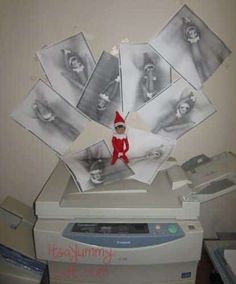 an elf is sitting on top of a printer in front of some pictures that have been cut out