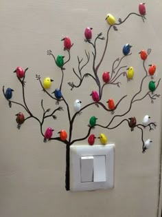 a decorative light switch cover with colorful birds on the tree and in the background is a white wall