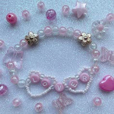 pink and white beaded bracelet with hearts, flowers, and butterflies on it's side