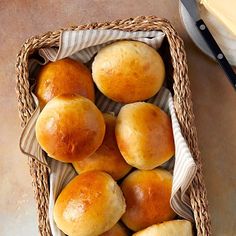 a basket filled with bread rolls on top of a table next to a butter knife