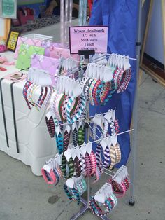 there are many different colored ties on display at this vendor's booth, and the price is $ 10