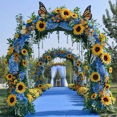 a blue and yellow wedding arch decorated with sunflowers, daisies and butterflies