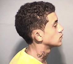 a man with tattoos on his neck and chest is looking to the side while wearing a yellow shirt