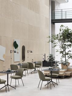 an empty restaurant with tables and chairs in front of a large stone wall that has plants growing on it