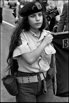 black and white photograph of a woman with long hair holding a baseball cap on her shoulder