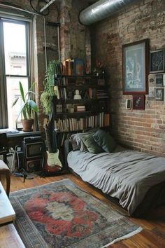 a bedroom with brick walls and lots of books on the shelves above the bed is filled with furniture