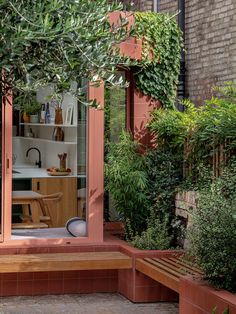 an outdoor area with wooden benches and potted plants on the side of the building